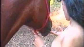 Adorable dark-haired girl is blowing a massive horse on the ranch